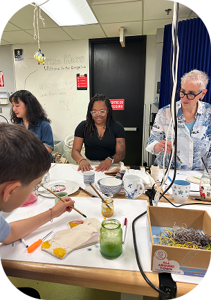 A group of people sitting around a table and painting
